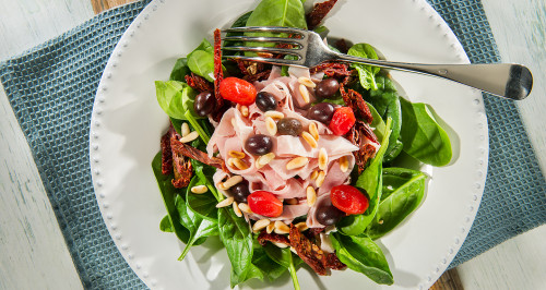 SALAD OF TENDER RAW SPINACH, HAM PIECES, TOASTED PINE NUTS, TAGGIASCA OLIVES AND SUN DRIED TOMATOES